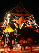 A large mobile-style hanging sculpture stands lit against the dark night sky.