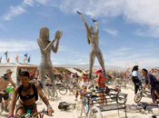 Two metal sculptures of human females, each over a story tall, loom over visitors at the entrance to a large tent.