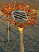 A sunflower made of copper petals surrounding a solar cell.
