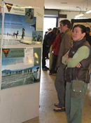 A woman at an exhibit stands reading a display of posters about Playa Restoration and Inspection.