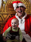 A baby appears terrified on the lap of Mr. Blue dressed as Santa