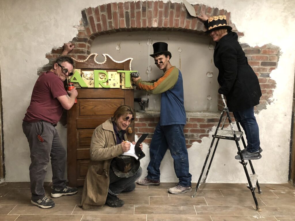 people creating a brick facade with a banner that says, 'art'