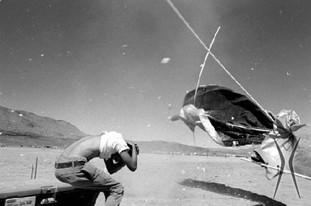 Burning Man participant in a strong wind with shade structure flying away.