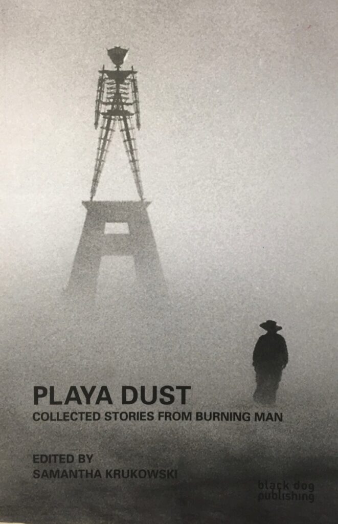 Book cover for Playa Dust – Collected Stories from Burning Man, edited by Samantha Krukowski showing The Man in a dust storm