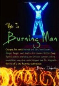 The Man with arms raised, glowing blue, with fire dancers in front. 