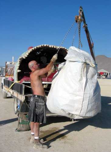 Really big white bag of trash being hoisted onto a trailer