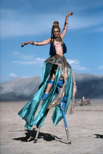 A person dancing on stilts with arms outstretched.