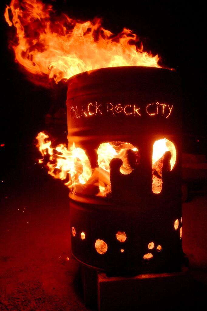A metal burn barrel with a roaring file inside flaming out the top 