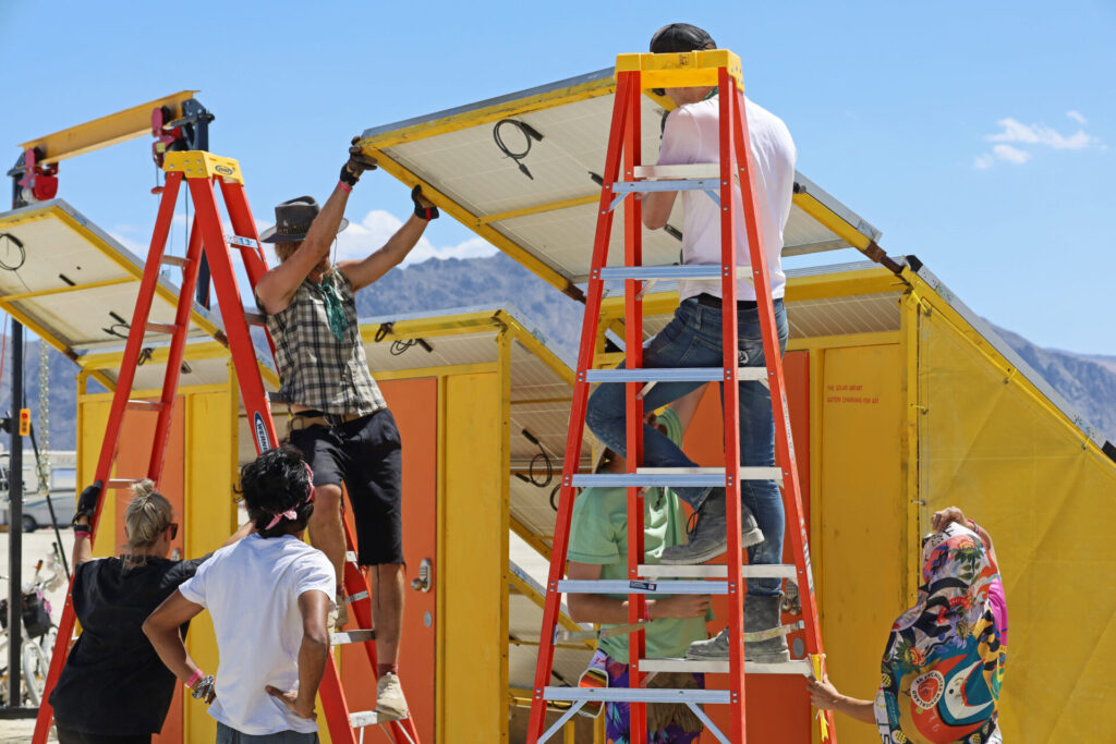 Artist Jered Ficklin and the Solarians install The Solar Library. A team of Burners installing a large solar panel.