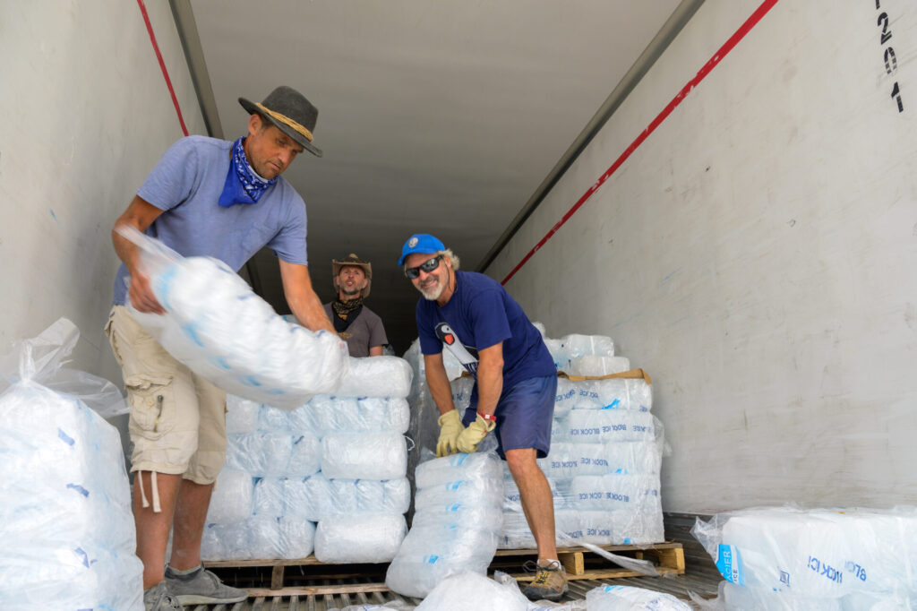 People unloading bags of ice from truck