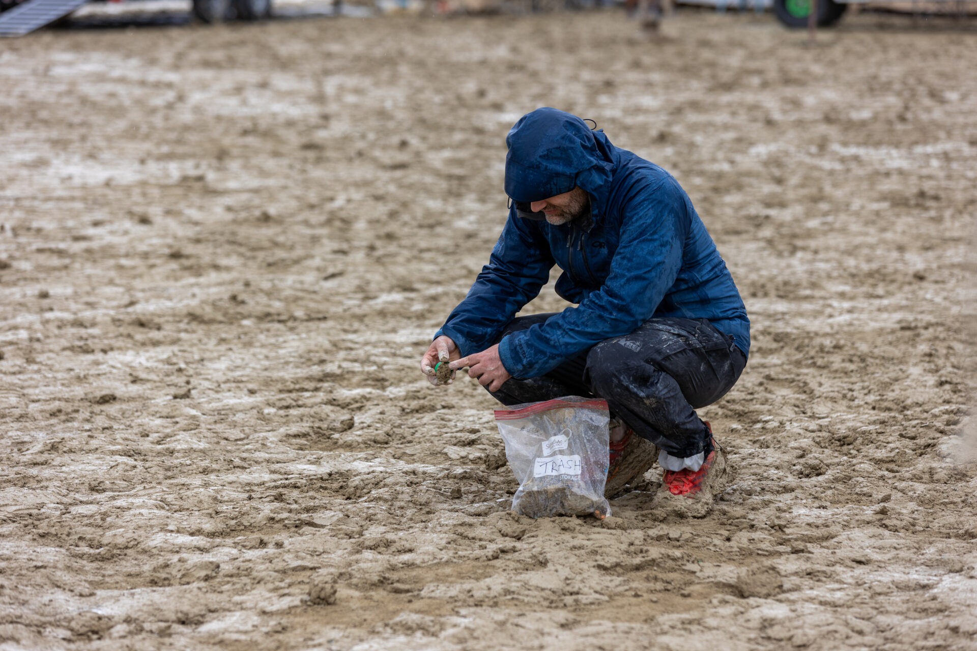Person squatting down picking up trash. 