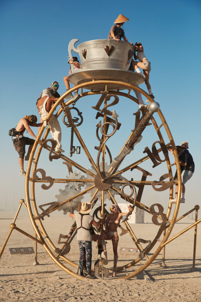 Participants climbing a warped clock at sunset