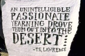 Hand written sign reads "An unintelligible passionate yearning drove them out into the desert -T.E. Lawrence"