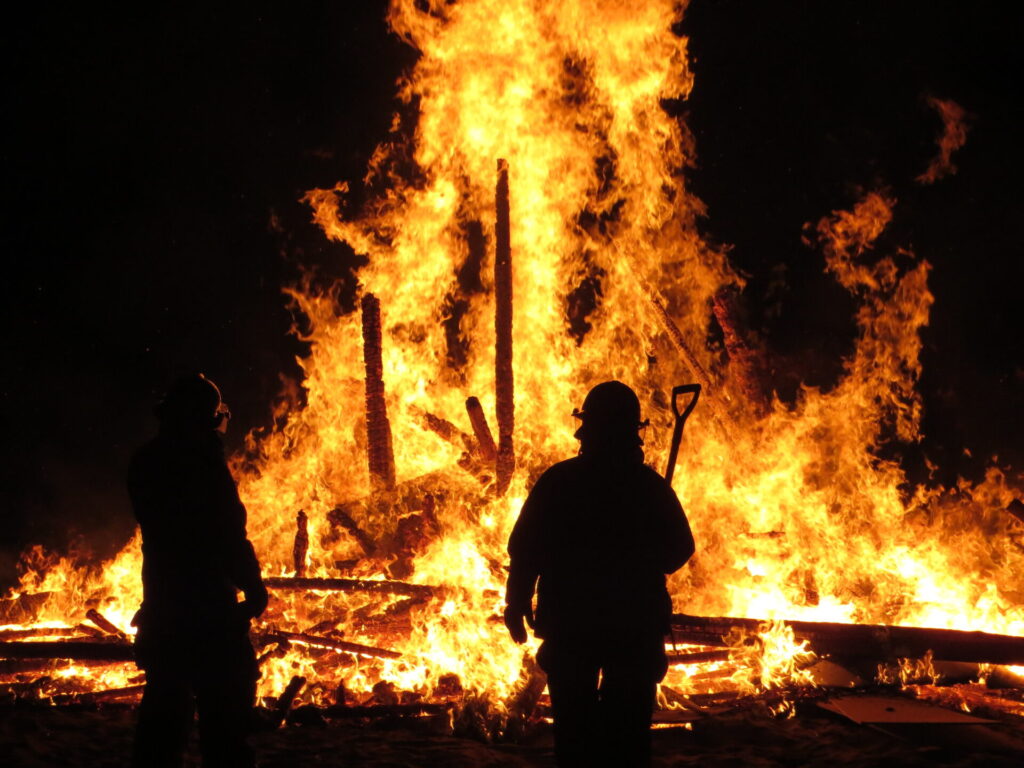 Firefighter silhouette in front of an sculpture on fire.