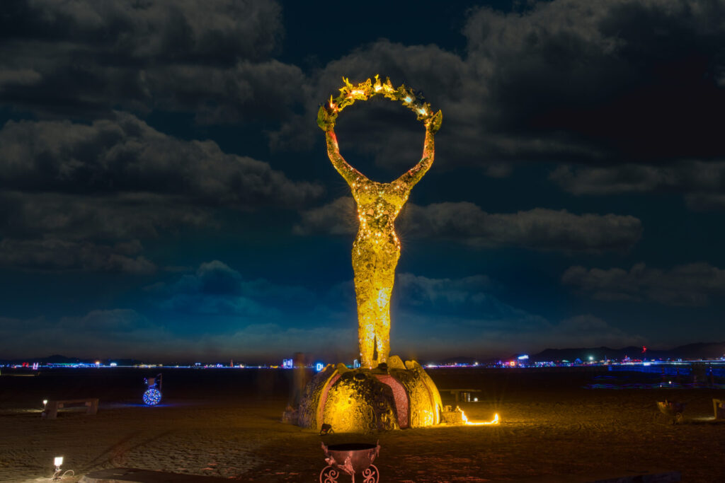 A. headless female form with arms raised and fingers touching