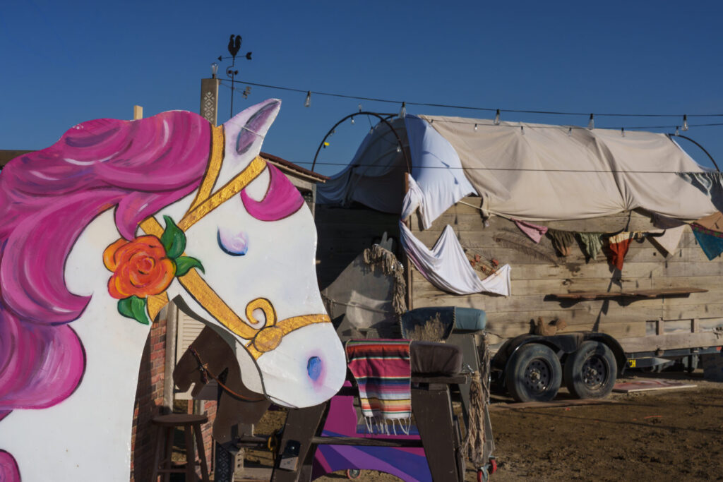 White horse with pink mane cut out in front of a camp.