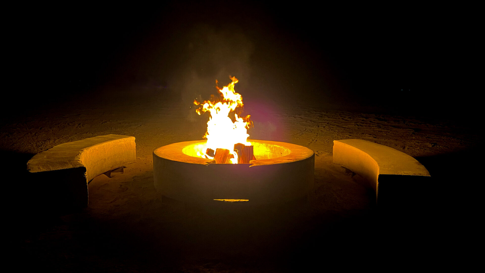 A circular cement fire pit with semicircle benches on two sides
