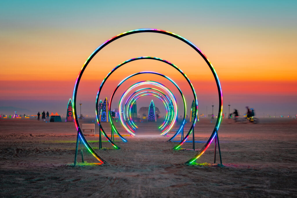 At sunset in Black Rock City an art installation of large circles with rainbow lights that you can walk or ride under.
