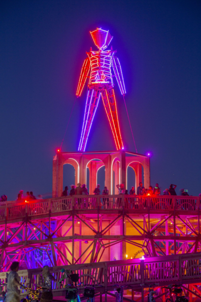 The man effigy lit with red and purple and the top of the base with participants walking up the ramps.