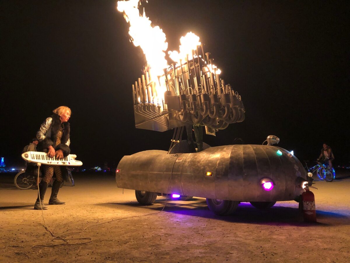 A flaming musical instrument mutant vehicle and operator.