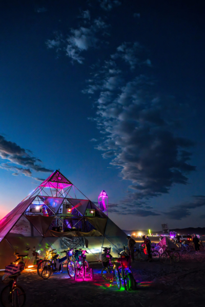 People enter a large pyramid structure just before dawn.