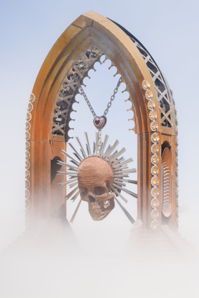 A skull with silver beams radiating light light beams from jaw to top of hear, hanging from a decorative arch.