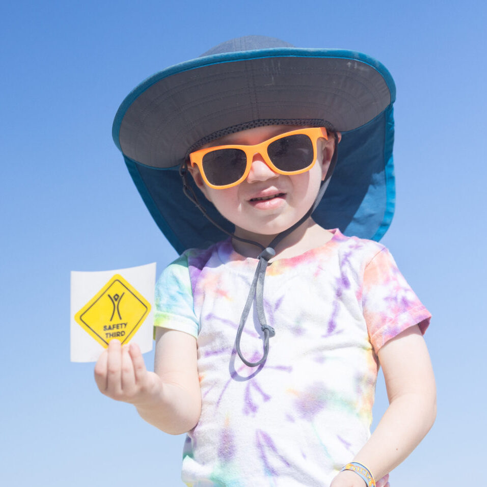 A child holds a sticker that says "Safety Third"