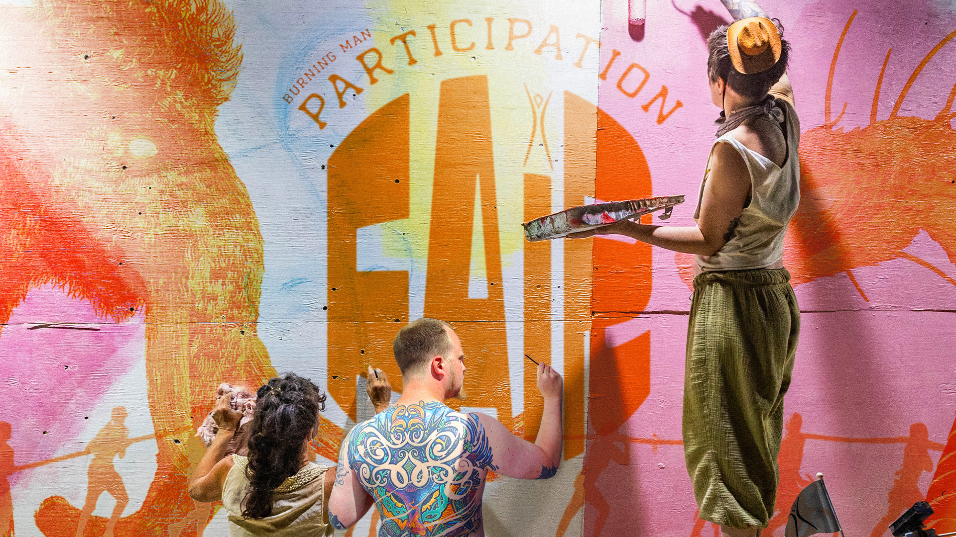 Three people collaboratively painting a wall mural.