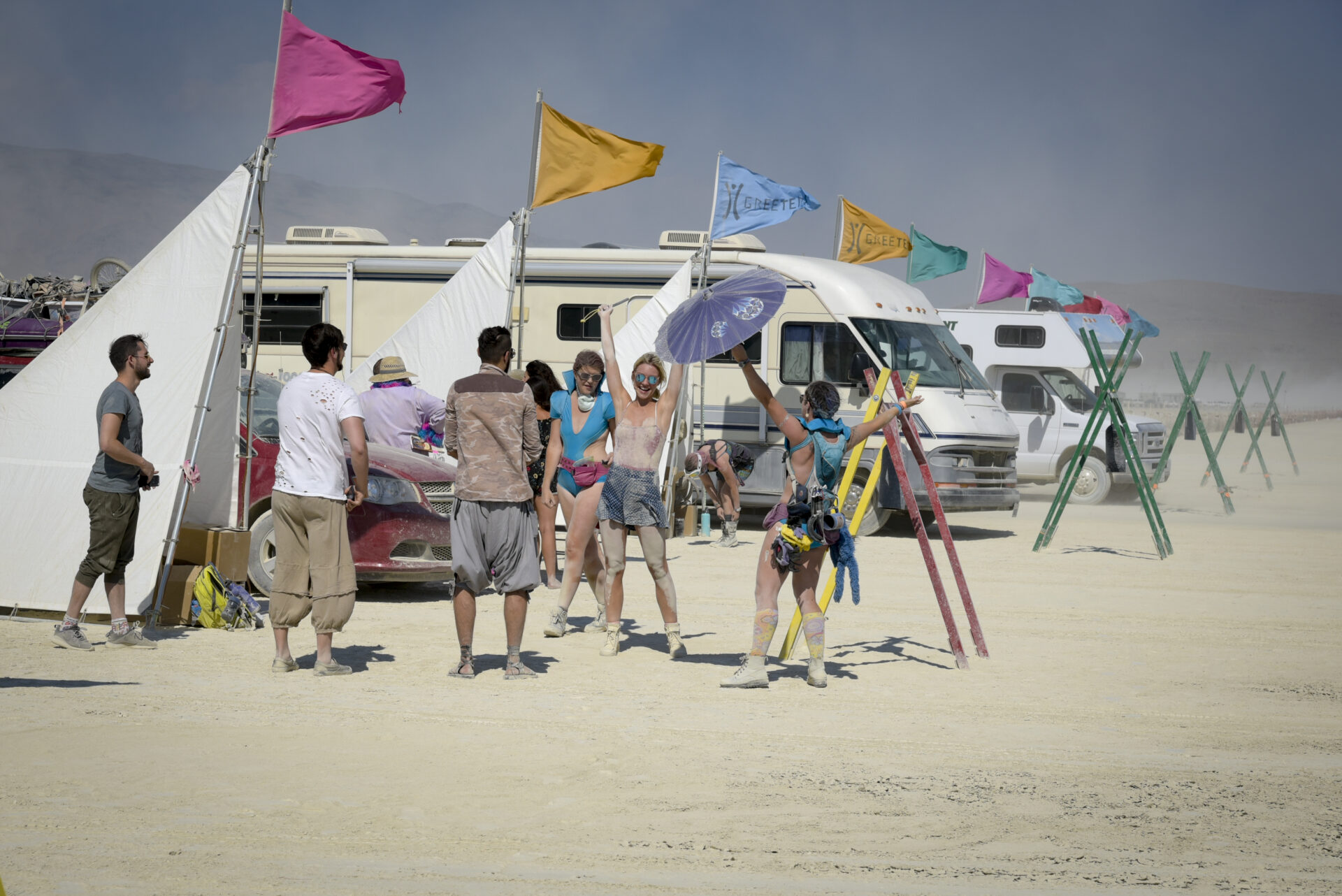 A group of people arms raised, as if preparing for a hug at Greeters in Black Rock City.