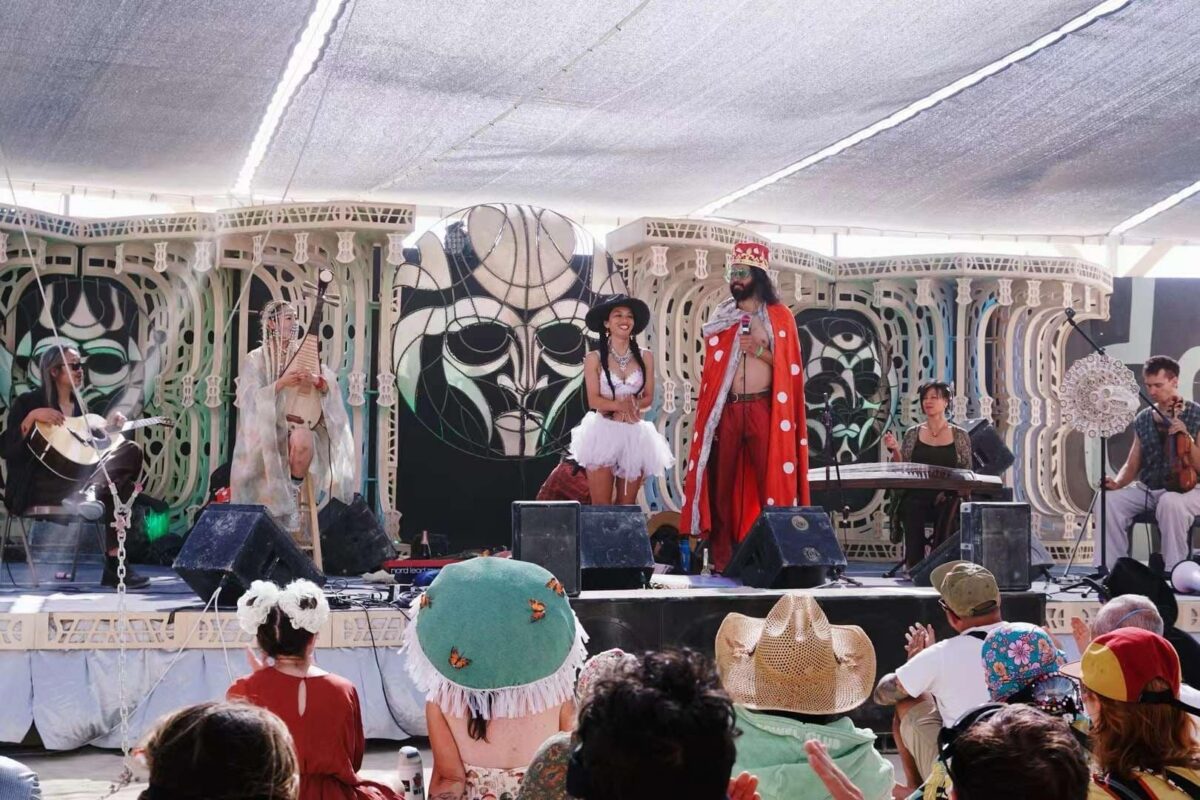 An audience sits by a stage where a band is performing.