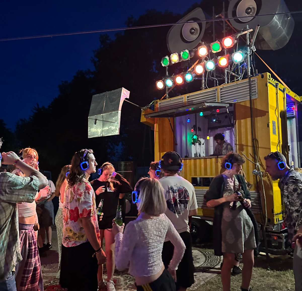 People wearing headphones stand in front of a DJ booth that is designed to look like the character Wall-E.