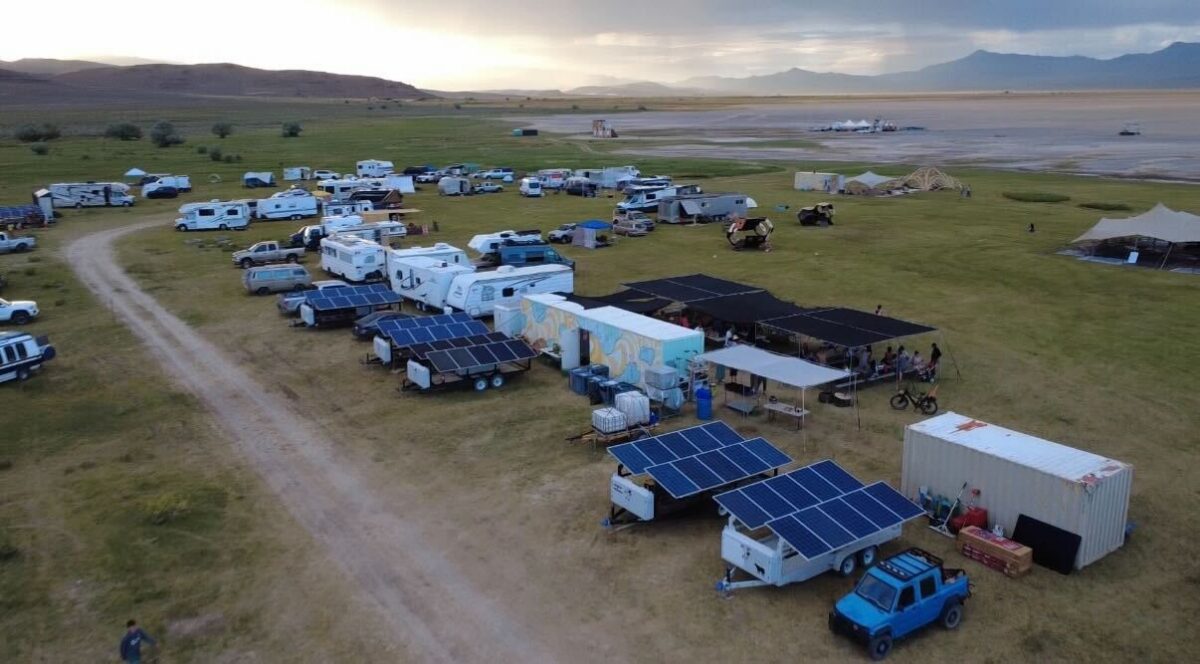 solar arrays, trailers and workers on a field near a lake