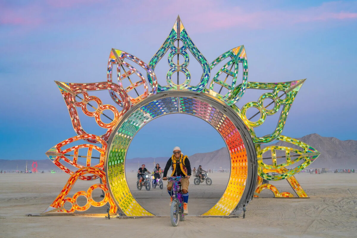 A person walks through a rainbow arch with decorative petals